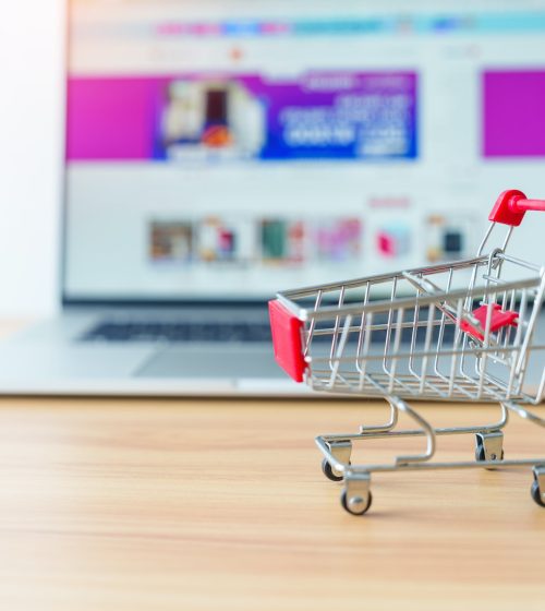 Shopping cart and laptop computer with marketplace website.